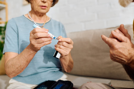 An elderly couple shares a tender moment as she helps him manage his diabetes at home.の写真素材