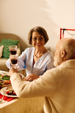 A senior couple enjoys their Christmas meal, raising their glasses in a toast filled with joy.の写真素材