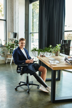 A young businessman with an artificial limb confidently works in a stylish office, embracing diversity.の写真素材