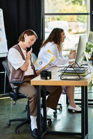 In a lively office, a young plus size woman laughs with her male friend at her desk.の写真素材