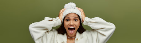 A cheerful woman with a bright smile enjoys the winter ambiance while wearing a cozy beanie.の写真素材