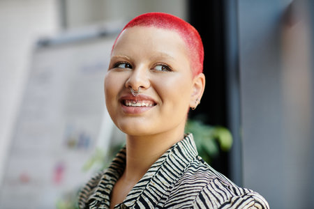 A bald woman with bright red hair smiles cheerfully in a stylish outfit, radiating confidence.の写真素材