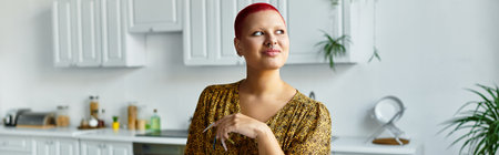 A bald woman with a radiant smile showcases her style in a contemporary kitchen filled with plantsの写真素材