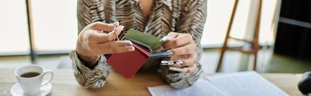 The beautiful bald woman examines vibrant fabric swatches as she sips her coffee in a bright space.の写真素材