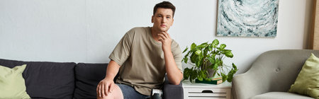 Young man sits on a couch, showcasing a modern and inviting space.の写真素材