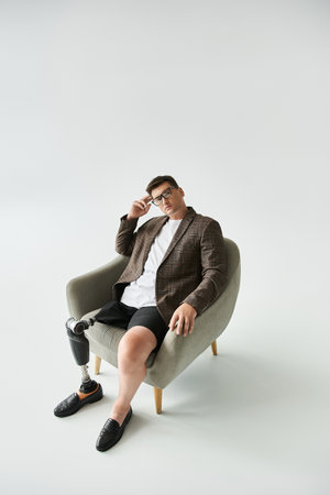 Handsome young man poses in a chair, showcasing his stylish outfit and prosthetic leg.の写真素材