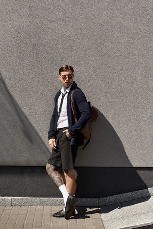 The young man displays his tattoos while wearing fashionable attire and sunglasses.の写真素材