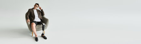 A young man with a prosthetic leg is seated in a contemporary chair, looking thoughtfully.の写真素材