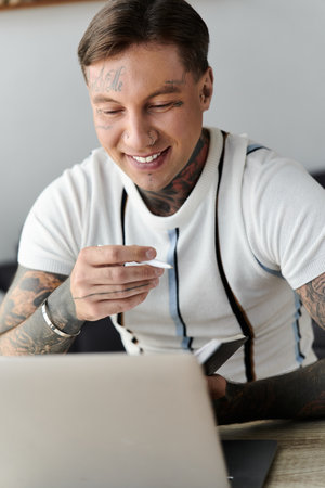 A young handsome man with tattoos enjoys his time while working on a laptop at home.の写真素材