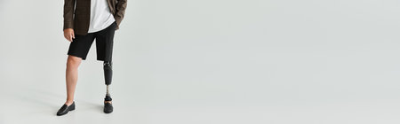 Young man stands with style, highlighting his prosthetic leg while dressed casually.の写真素材