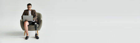 Handsome young individual with a prosthetic leg focused on his laptop while seated comfortably.の写真素材