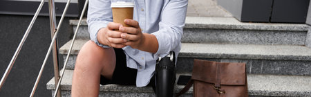 Handsome young man sits on steps, holding coffee cup and showing off prosthetic leg with confidence.の写真素材