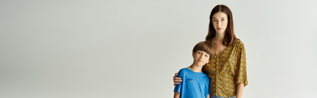 A young mother and her son stand together in casual clothes, showcasing their bond in a studio.の写真素材