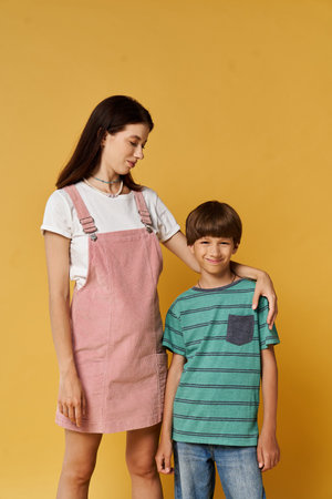 A young mother and her son bond in casual attire against a vibrant yellow backdrop.の写真素材