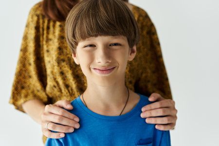 A young mother embraces her son, both smiling happily while dressed in casual attire.の写真素材