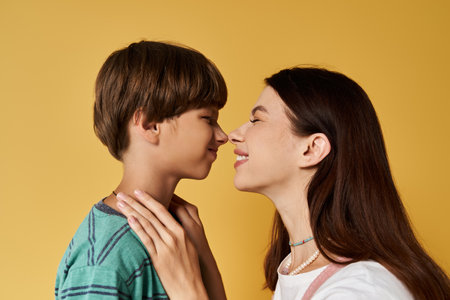 A young mother and her son share a playful moment, smiling at each other in a studio.の写真素材