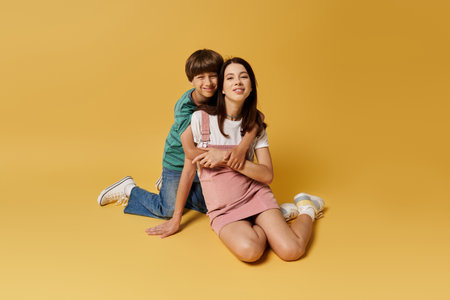 A young mother and her son share a playful moment, embracing in a vibrant studio filled with warmth.の写真素材