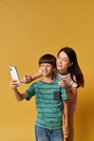 A young mother and her son enjoy taking selfies together, showcasing their playful bond.の写真素材