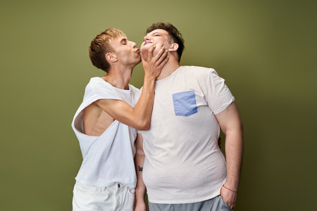 A queer couple joyfully kisses, celebrating love and connection in a cozy indoor setting.の写真素材