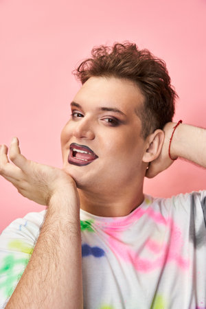 Individual showcases bold queer style with vibrant makeup and joyful attitude in bright setting.の写真素材
