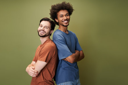 Two friends stand back to back, beaming with happiness in a colorful, inclusive atmosphere.の写真素材