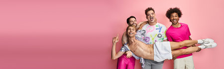 Four friends celebrate their true selves with laughter and colorful outfits on a pink backdrop.の写真素材