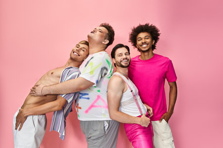 Four individuals express joy and solidarity in colorful attire against a bright pink backdrop.の写真素材