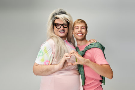 Two individuals express their love while showcasing pride and vibrant styles in a studio setting.の写真素材
