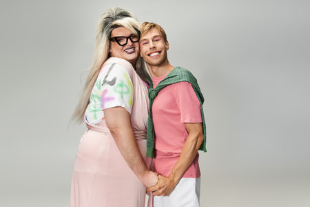 Two individuals embrace and smile, showcasing their vibrant styles and celebrating queer identity.の写真素材