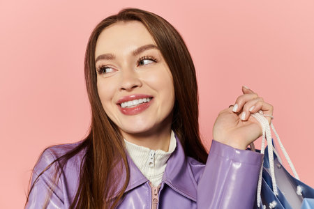 Stylish woman beams with joy, showcasing her trendy outfit while holding a colorful bag.の写真素材