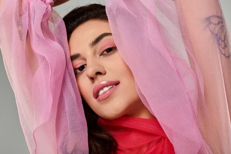 A young beautiful woman showcases her elegance in flowing pink fabric, radiating confidence.の写真素材