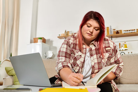 Young woman enjoys her creative process at home, capturing thoughts in a cozy environment.の写真素材