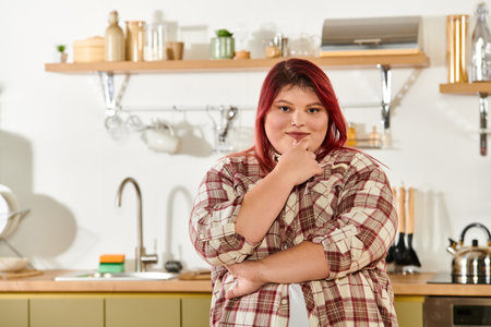 Stylish young woman stands in chic kitchen, showcasing her confidence and radiant smile.の写真素材