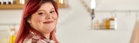 Plus size woman smiles confidently while preparing a meal in a vibrant kitchen space.の写真素材