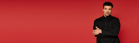 Handsome young man stands with arms crossed, showing a relaxed yet assured expression.の写真素材