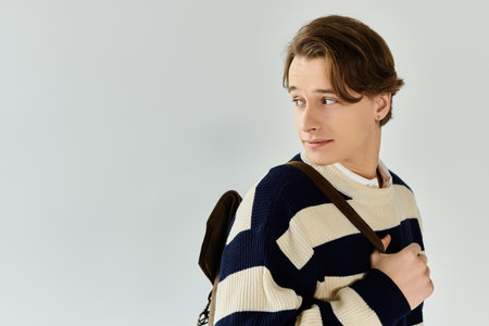 A young student showcases his style in a striped sweater, embodying youth culture and fashion.の写真素材