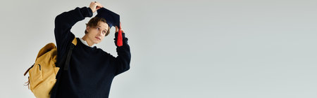 A handsome young man adjusts his graduation cap, showcasing pride in his achievement during college,...