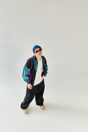 Young man wearing a trendy bomber jacket showcases his personal style in a creative studio.