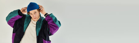 A young man shows off his fashion sense in a colorful bomber jacket while posing.の写真素材