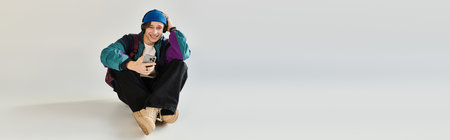 A handsome young man in a trendy bomber jacket relaxes and smiles while seated in a studio.の写真素材