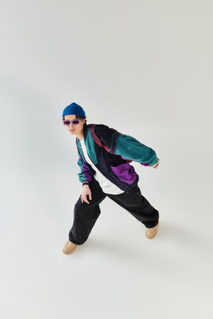 A young man showcases his fashion sense in a sleek bomber jacket while striking a pose in a studio.