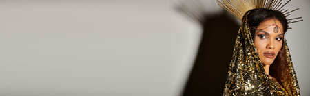 An enchanting goddess radiates beauty in a shiny golden dress, evoking divine charm in a studio.の写真素材