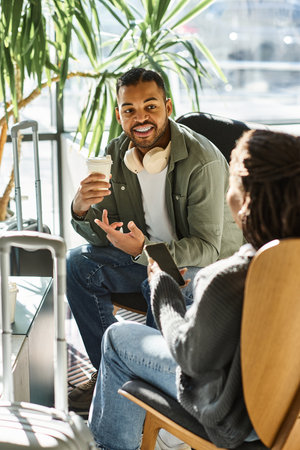 Two young African American travelers relax in a hotel lobby, enjoying drinks and good conversation.の写真素材