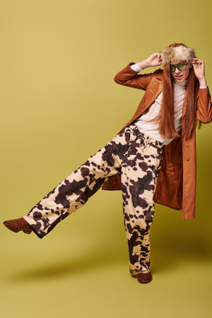 A young man with long red hair joyfully poses in a vibrant outfit against a bold backdrop.の写真素材