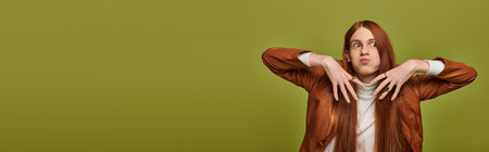 Young man with striking long red hair showcases a range of emotions against a green backdrop.の写真素材