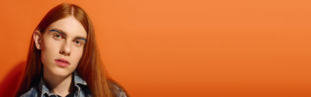A young man with long red hair displays a range of emotions in a vivid orange setting.