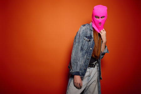 A young man expresses deep emotions while posing in a colorful outfit with long red hair.の写真素材