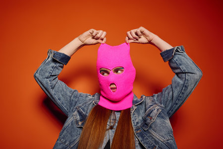 Emotional young man showcases vibrant feelings while wearing a striking pink ski mask.の写真素材