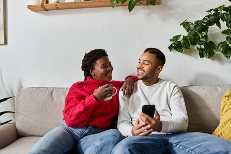 A joyful Black couple shares quality time in their living room on a chilly winter day.