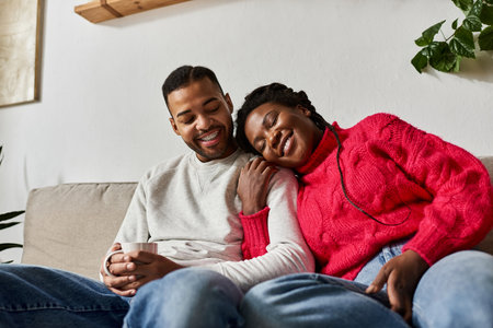 A joyful couple relaxes on the couch, enjoying each other's company on a chilly winter day.